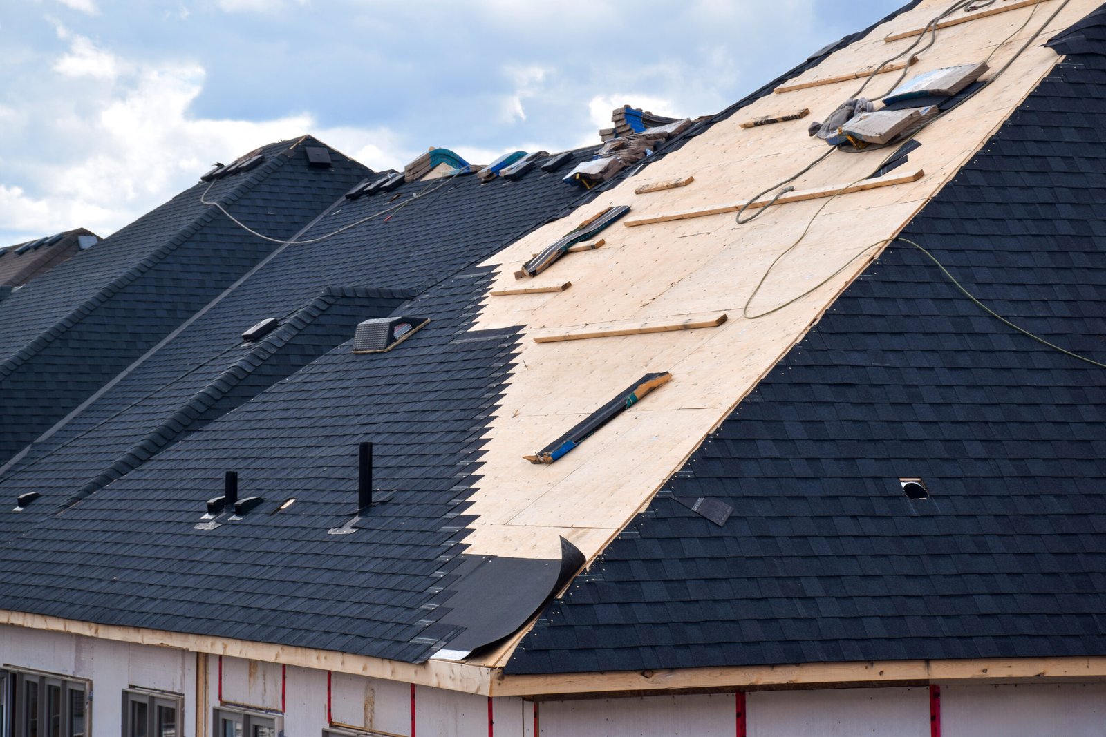 Closeup installation of black roof shingles on new residential h